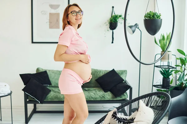Zwangere Jonge Vrouw Roze Pyjama Glazen Die Overdag Binnen Staan — Stockfoto