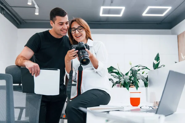 Siyah elbiseli bir adam, kadının fotoğrafçı kamerasından fotoğraf izliyor..