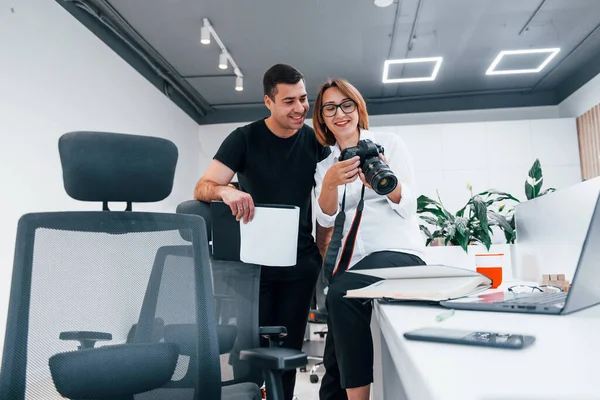 Siyah elbiseli bir adam, kadının fotoğrafçı kamerasından fotoğraf izliyor..