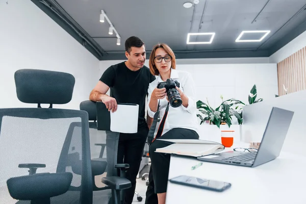 Siyah elbiseli bir adam, kadının fotoğrafçı kamerasından fotoğraf izliyor..