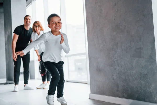 Resmi giyinmiş bir kadın ve elinde kamerayla boş bir odada koşan ve eğlenen bir adamla..