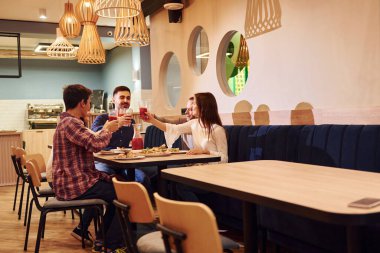 Evde oturup pizza yiyen bir grup genç arkadaş..