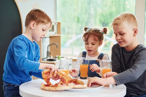 Three Children Sitting Indoors Table Eating Pizza Orange Juice Together — Stock Photo, Image