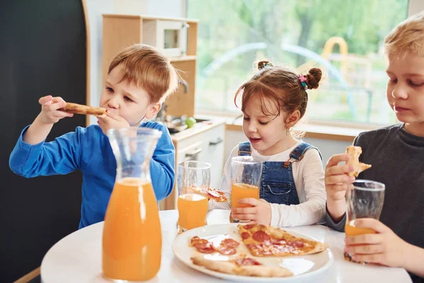 Three Children Sitting Indoors Table Eating Pizza Orange Juice Together — Stock Photo, Image