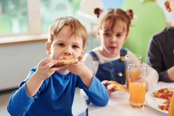 Three Children Sitting Indoors Table Eating Pizza Orange Juice Together — Stock Photo, Image