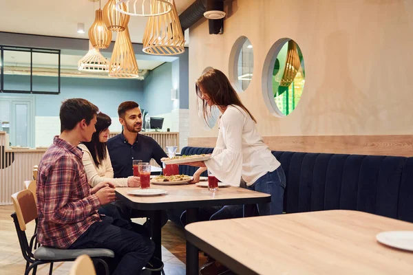 Evde oturup pizza yiyen bir grup genç arkadaş..