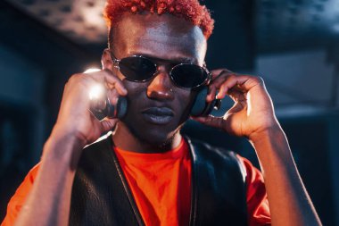 Genç Afrikalı Amerikalı sanatçı bir kayıt stüdyosunda duruyor ve kulaklık takıyor..