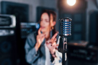 Mikrofona yakından bak. Genç ve güzel bir bayan sanatçı bir kayıt stüdyosunda prova yapıyor..