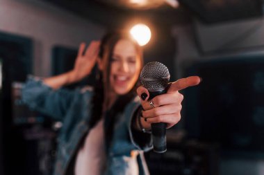 Mikrofona yakından bak. Genç ve güzel bir bayan sanatçı bir kayıt stüdyosunda prova yapıyor..