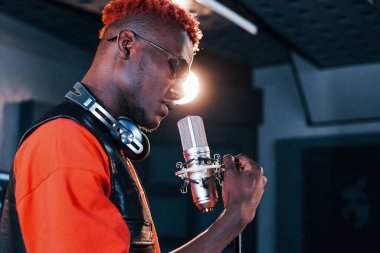 Genç Afrikalı Amerikalı sanatçı bir kayıt stüdyosunda prova yapıyor..