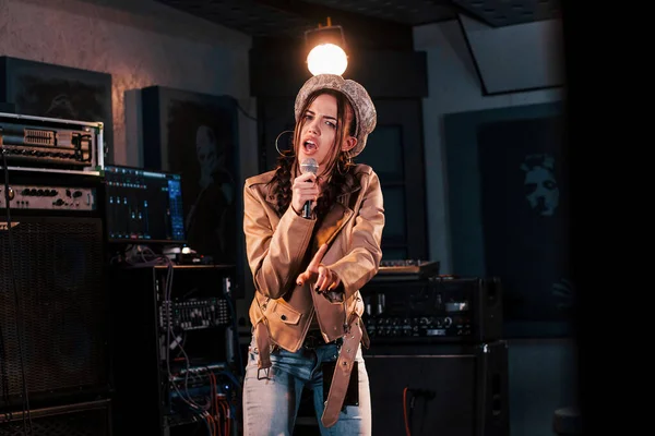 Genç ve güzel bir bayan sanatçı bir kayıt stüdyosunda prova yapıyor..