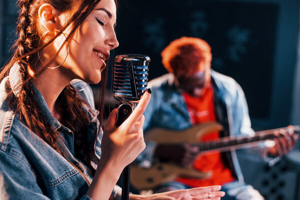 Guy plays guitar, girl sings. African american man with white girl rehearsing in the studio together.