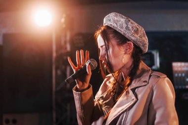 Young beautiful female singer rehearsing in a recording studio.