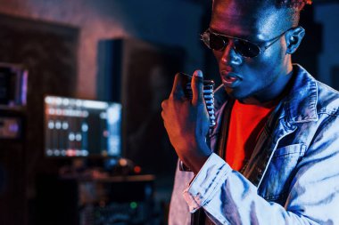Genç Afrikalı Amerikalı sanatçı bir kayıt stüdyosunda prova yapıyor..