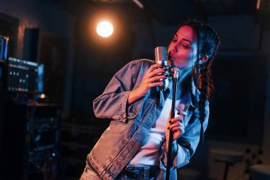 Genç ve güzel bir bayan şarkıcı bir kayıt stüdyosunda prova yapıyor..