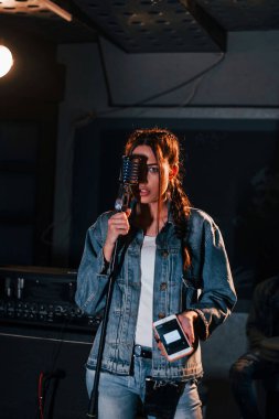 Genç ve güzel bir bayan sanatçı bir kayıt stüdyosunda prova yapıyor..