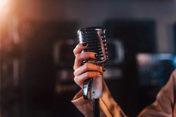 stock image Close up view of microphone. Young beautiful female performer rehearsing in a recording studio.