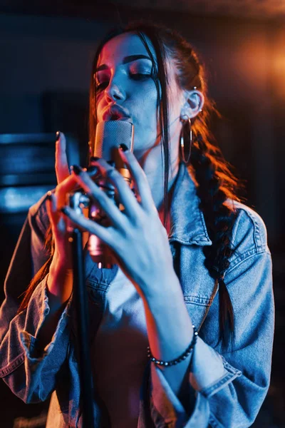 Genç ve güzel bir bayan şarkıcı bir kayıt stüdyosunda prova yapıyor..