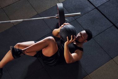 Yerde oturuyordum. Spor elbiseli güçlü Afrikalı Amerikalı adam spor salonunda antrenman yapıyor..