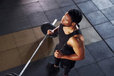 Üst Manzara. Halter yere düştü. Spor elbiseli güçlü Afrikalı Amerikalı adam spor salonunda antrenman yapıyor..