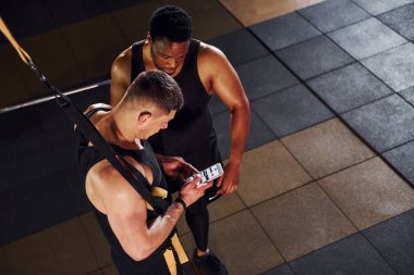 Ara verdim ve telefon kullandım. Beyaz adamla Afrika kökenli Amerikalı bir adam spor salonunda antrenman yapıyor..