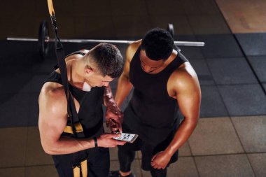 Ara verdim ve telefon kullandım. Beyaz adamla Afrika kökenli Amerikalı bir adam spor salonunda antrenman yapıyor..