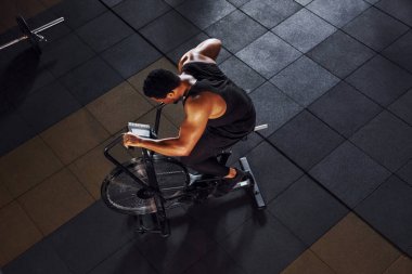 Bisiklete binmek. Spor elbiseli güçlü Afrikalı Amerikalı adam spor salonunda antrenman yapıyor..