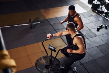 Beyaz adamla Afrika kökenli Amerikalı bir adam spor salonunda antrenman yapıyor..