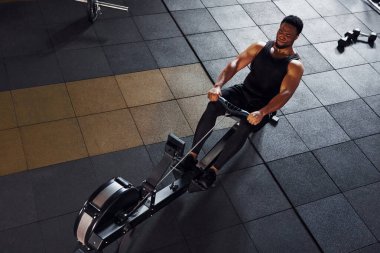 Güçlü Afro-Amerikan spor elbiseli adam spor salonunda spor yapıyor ve ekipman kullanıyor. Güç ve güç kavramı.