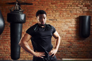 Spor elbiseli güçlü Afro-Amerikan adam spor salonunda duruyor..