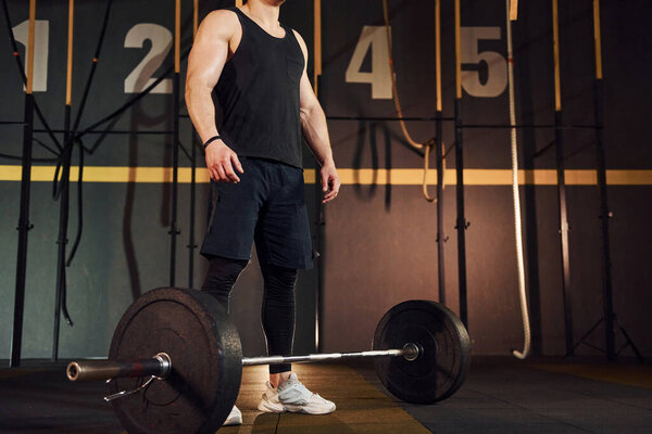 Strong man in sportive clothes lifting barbell in the gym.