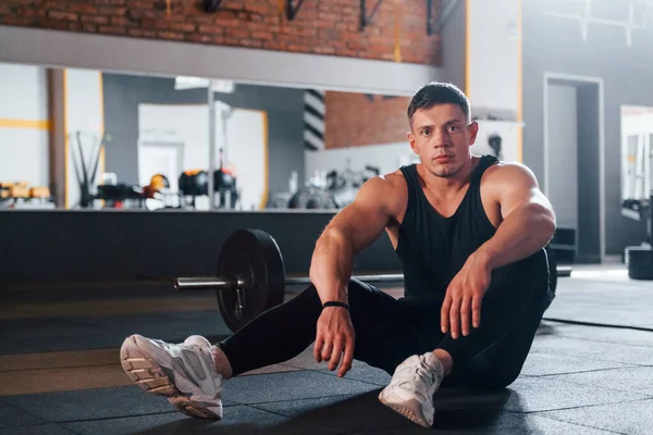 Spor kıyafetli güçlü adam spor salonunda antrenman yapıyor..