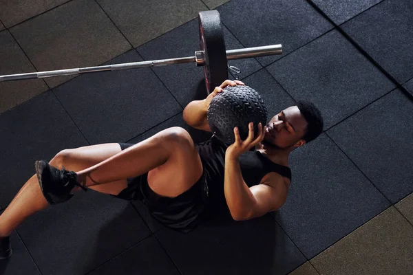 Yerde oturuyordum. Spor elbiseli güçlü Afrikalı Amerikalı adam spor salonunda antrenman yapıyor..