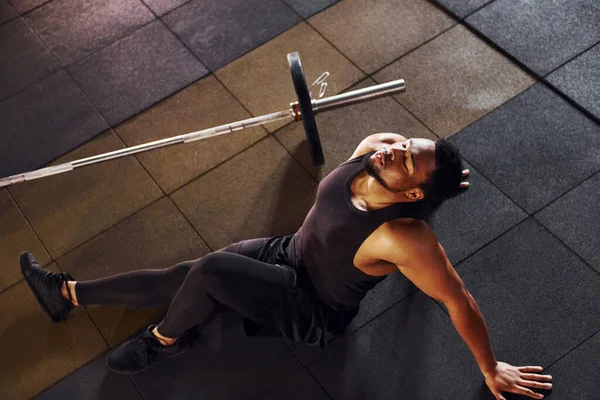 Yerde oturuyordum. Spor elbiseli güçlü Afrikalı Amerikalı adam spor salonunda antrenman yapıyor..