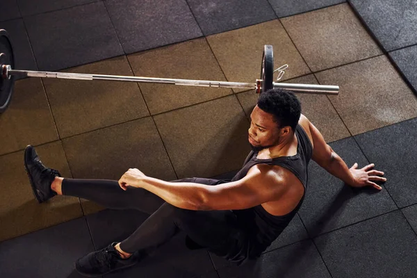 Yerde oturuyordum. Spor elbiseli güçlü Afrikalı Amerikalı adam spor salonunda antrenman yapıyor..
