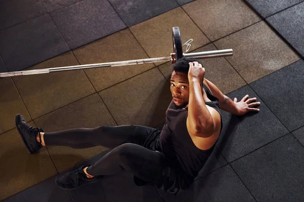 Yerde oturuyordum. Spor elbiseli güçlü Afrikalı Amerikalı adam spor salonunda antrenman yapıyor..