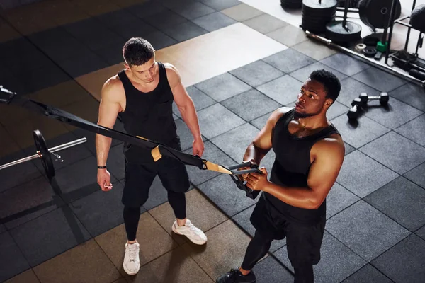 Kişisel antrenör iş başında. Beyaz adamla Afrika kökenli Amerikalı bir adam spor salonunda antrenman yapıyor..