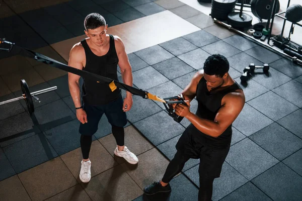Kişisel antrenör iş başında. Beyaz adamla Afrika kökenli Amerikalı bir adam spor salonunda antrenman yapıyor..