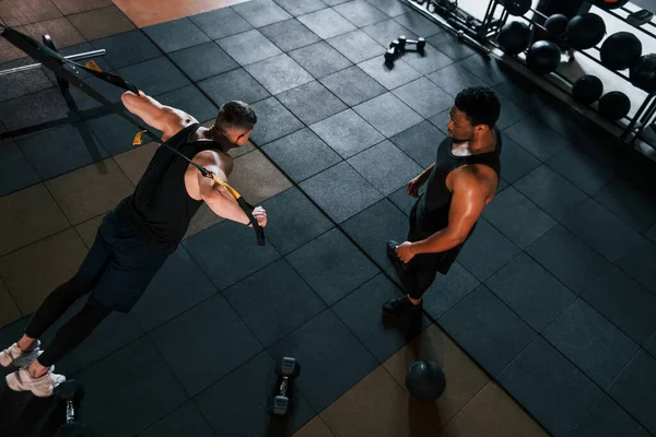 Kişisel antrenör iş başında. Beyaz adamla Afrika kökenli Amerikalı bir adam spor salonunda antrenman yapıyor..