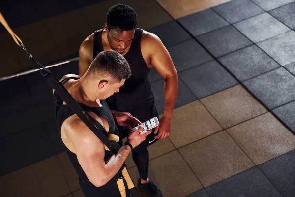 Ara verdim ve telefon kullandım. Beyaz adamla Afrika kökenli Amerikalı bir adam spor salonunda antrenman yapıyor..