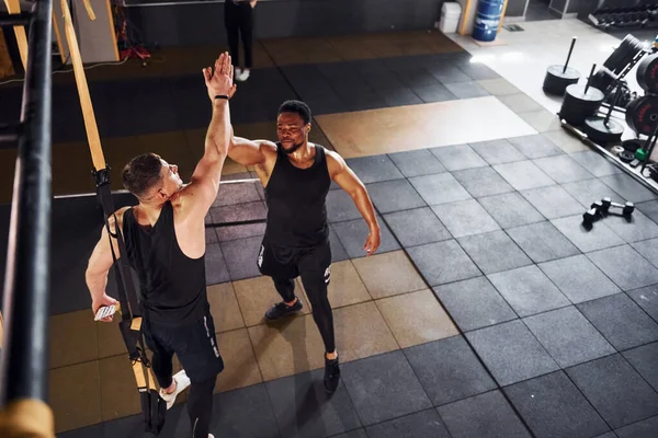 Çak bir beşlik. Beyaz adamla Afrika kökenli Amerikalı bir adam spor salonunda antrenman yapıyor..