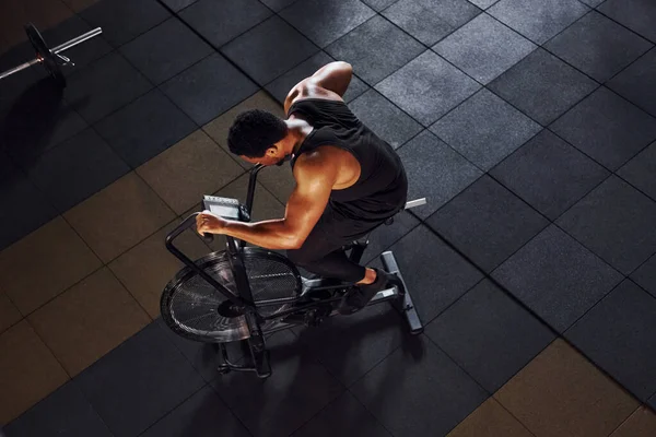 Bisiklete binmek. Spor elbiseli güçlü Afrikalı Amerikalı adam spor salonunda antrenman yapıyor..