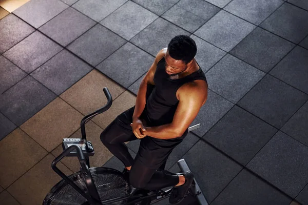 Bisiklete binmek. Spor elbiseli güçlü Afrikalı Amerikalı adam spor salonunda antrenman yapıyor..