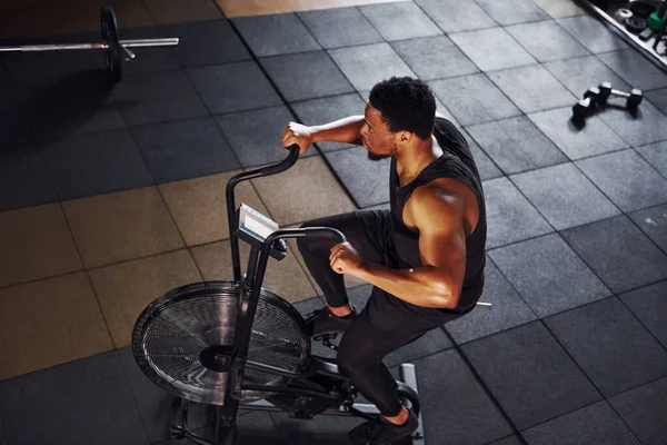 Bisiklete binmek. Spor elbiseli güçlü Afrikalı Amerikalı adam spor salonunda antrenman yapıyor..