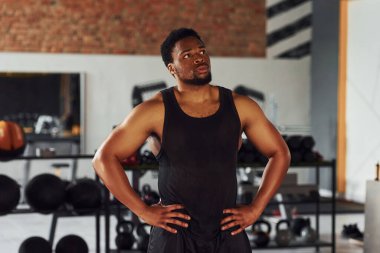Spor elbiseli güçlü Afro-Amerikan adam spor salonunda duruyor..