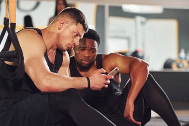 Ara verdim ve telefon kullandım. Beyaz adamla Afrika kökenli Amerikalı bir adam spor salonunda antrenman yapıyor..