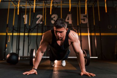 Spor kıyafetleri içinde güçlü bir adam spor salonunda şınav çekiyor..