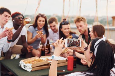 Lezzetli pizzayla. Gündelik giysiler içinde bir grup genç gündüz vakti çatıda parti veriyor..