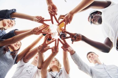 Parmaklarıyla güzel bir jest yapıyor. Aşağıdan bak. Gündelik giysiler içinde bir grup genç gündüz vakti çatıda parti veriyor..