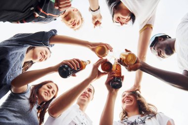 Aşağıdan bak. Şerefe içiyorum. Gündelik giysiler içinde bir grup genç gündüz vakti çatıda parti veriyor..